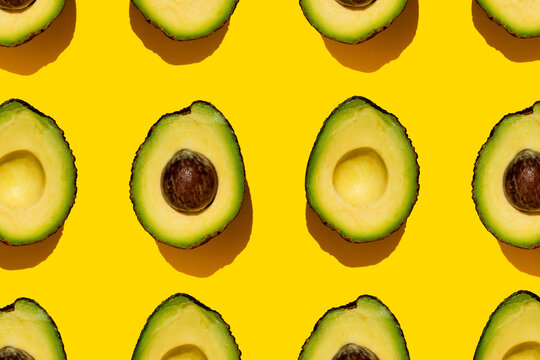 Pattern of halved avocados on yellow background