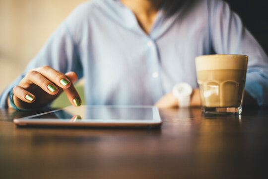 Woman sitting in a cafe using a digital tablet and drinking a coffee