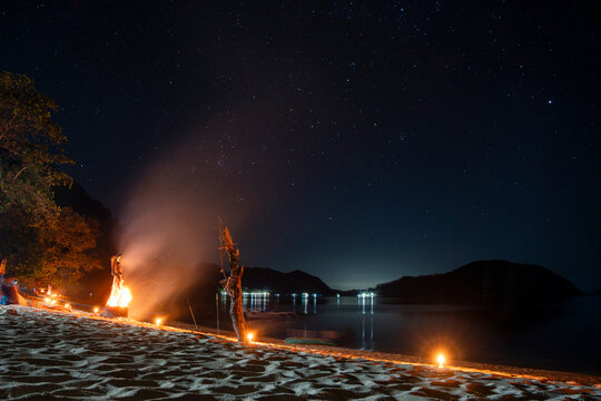 A campfire illuminates the sand at night in El Nido