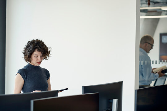 Businesswoman reading folder in modern London office with colleague