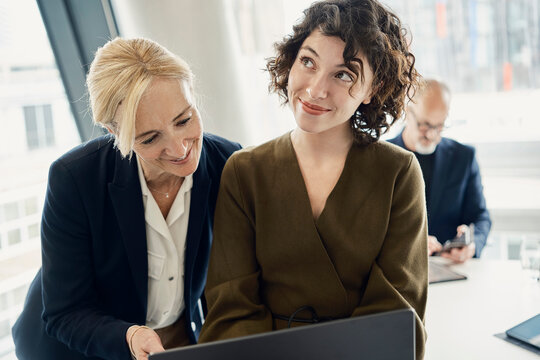 Businesswoman and colleague use a laptop at a modern London office