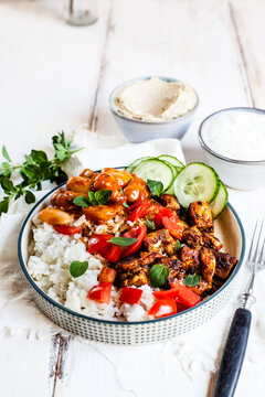 Bowl of Greek gyro with rice, fava beans, halloumi cheese, tomatoes and cucumbers