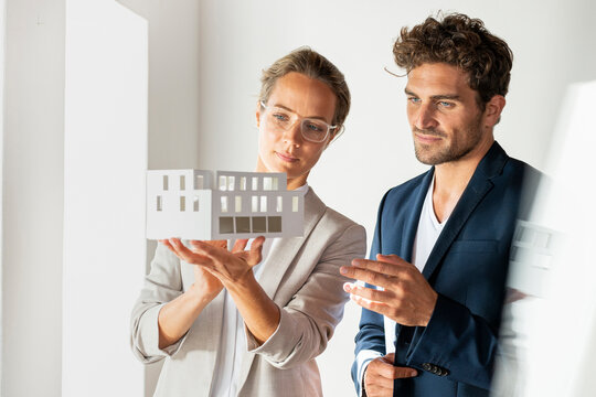 Businesswoman with house model standing by colleague at office