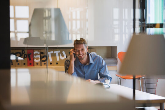Business professional smiling and talking on phone in modern office