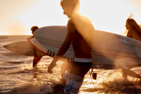 Surfers in the sea at sunset