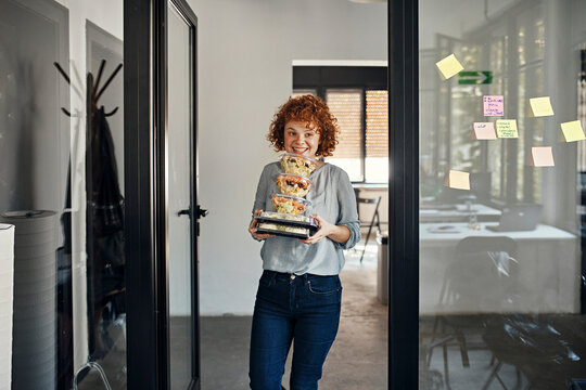 Smiling businesswoman serving takeaway food in office