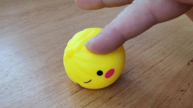 Rolling a squishy anti-stress toy across a table with your fingers to relieve stress and tension. Cute, soft, yellow sensory toy on an office desk. Moldova, Chisinau, July 2, 2026.