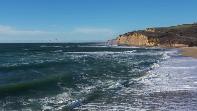 Midday drone smooth glide beach waves kitesurfers
