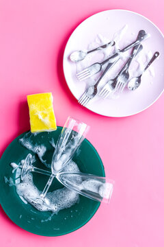 Washing dishes concept. Plates, spoons, forks on pink background top view