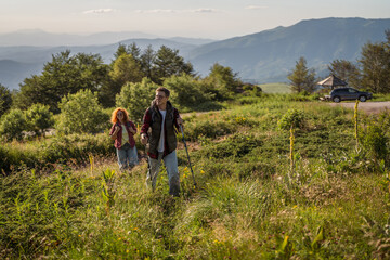 Obraz premium Couple hiking a mountain trail with backpacks and trekking poles