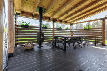 Obraz premium Wide View of Covered Wooden Terrace with Stove and Dining Area