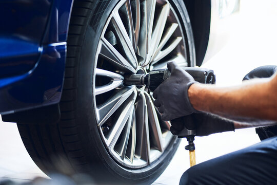 Mechanic using pneumatic wrench to change tire in auto garage