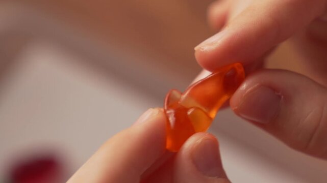 Close-up of an orange gelatin dolphin in children's fingers, sweet candy.