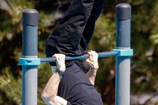 Person performs pull-up on outdoor gym bar