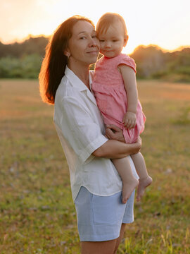 Family moment with mother and her little daughter outdoor with sunset in park