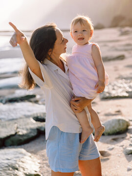 Mother with her baby girl on sea beach with sunshine. Happy moments