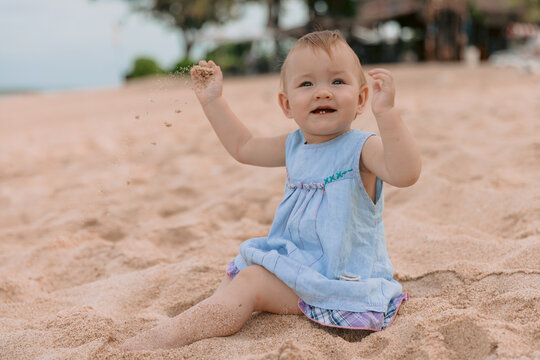 Beautiful girl in outdoor. Baby in blue dress on sandy beach.