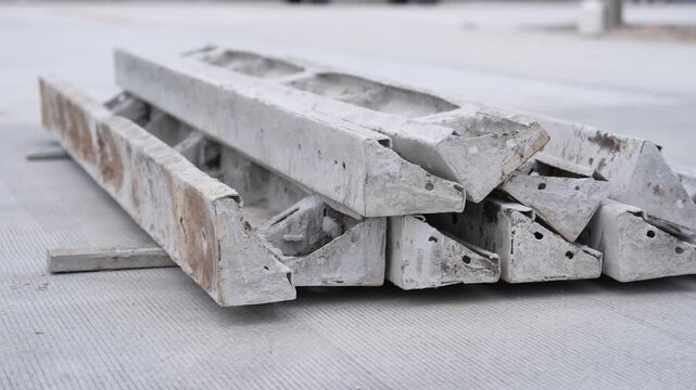 Concrete beam precast construction slab rubble material stacked debris demolition recycling on pavement, industrial gray structural elements for renovation, repair, infrastructure work
