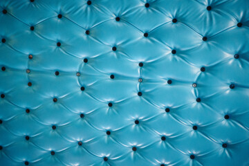 Obraz premium Close-up of a vibrant blue tufted leather surface with button details, showcasing a diamond pattern and glossy texture.