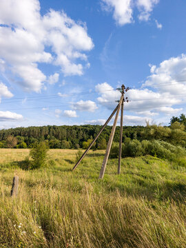 Wooden Power Pole Standing in Open Green Field Under Clouds