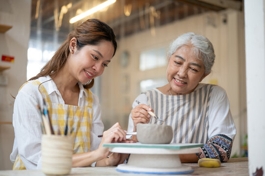 Asian women different generations working together on pottery enjoying creative workshop with smiles