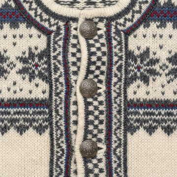 Close-up shot of a cream knitted garment featuring traditional Nordic patterns and snowflake motifs, with ornate silver buttons.
