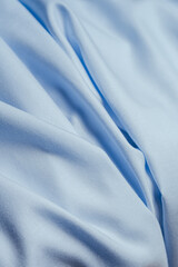 Fototapeta premium Close-up of soft light blue cotton fabric with natural folds creating an elegant textile background.