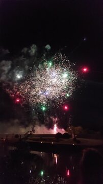 Feu d'artifice qui illumine le ciel nocturne avec des explosions &eacute;clatantes de couleurs rouges, vertes, dor&eacute;es et blanches.