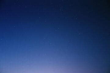 Fototapeta premium The Starry Night Sky Over a Quiet Horizon With Soft Blue Glow