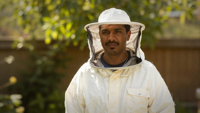 male beekeeper in protective suit and veil looking at the camera