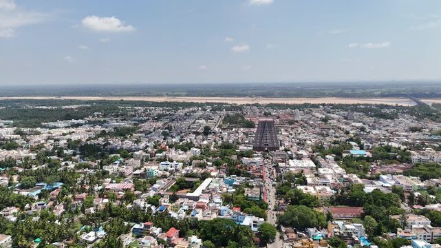 Wide aerial panorama of Sri Ranganathaswamy Temple featuring the towering temple gopuram, traditional neighborhoods, tropical greenery, and the Kaveri riverbed in the distance. spiritual heart of TN