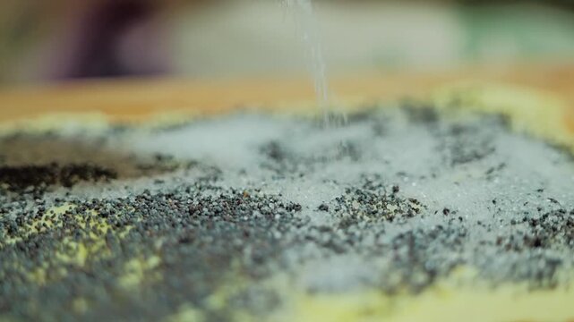 Slow motion, sugar falling onto poppy seed pastry before homemade cookie baking