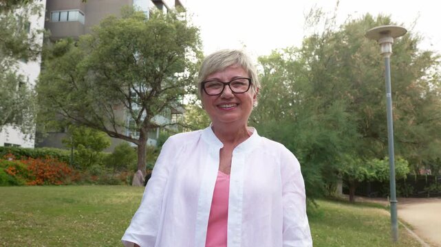 Happy senior woman with glasses laughing in the park