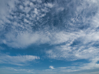 Clear blue sky with thin white clouds forming patterns resembling fish scales or ripples—specifically cirrocumulus clouds often referred to as a buttermilk sky. © saksuvan