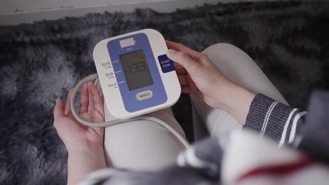 Close-up of a digital blood pressure monitor on a woman's arm, conveying home health monitoring, patient care, medical measurement and remote wellness tracking.