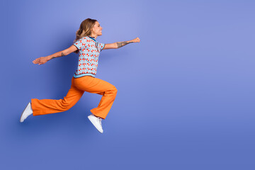 Obraz premium Happy young female leaps in stylish outfit against violet background showcasing fashion joy energy and lifestyle