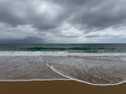 Dramatic Stormy Sky Over Ocean Waves and Sandy Beach