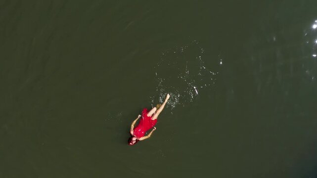  Aerial view of gorgeous woman in red dress floating on calm water