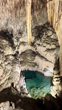 Dark scene nature view inside dark dragon cave. Tourist attraction: caves stalactites and stalagmites rock formations blue water lake. town Porto Cristo Mallorca Spain. vertical video Cuevas del Drach