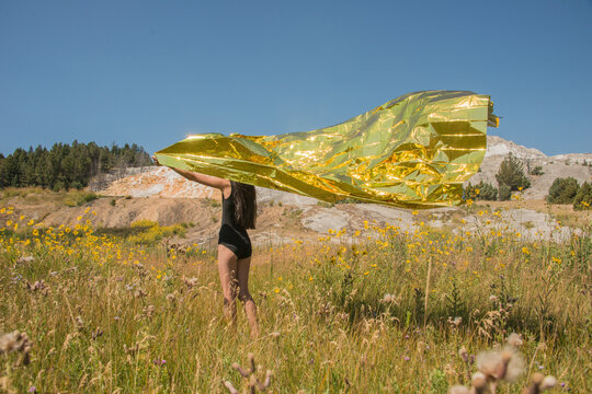 art portrait of girl in the field holding shiny golden foil  sheet
