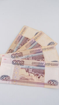 Vertical close up photograph of four five hundred russian ruble banknotes fanned out on a white surface