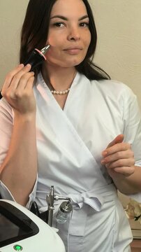 Beauty therapist presents a phonophoresis device applicator in a salon, professional skincare equipment, cosmetic technology, treatment demonstration.