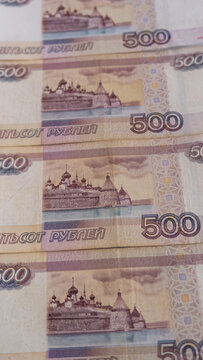Vertical close up photograph of several five hundred russian ruble banknotes overlapping to form a pattern
