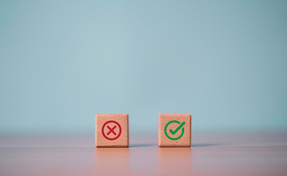 Wooden blocks with red cross and green check symbols, representing right and wrong choices, decision making, quality control, approval, rejection, evaluation, and business standards.