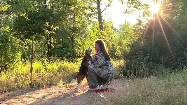 Female dog owner practices commands with a beagle outdoors, pet obedience, canine training, focused interaction, animal companionship.
