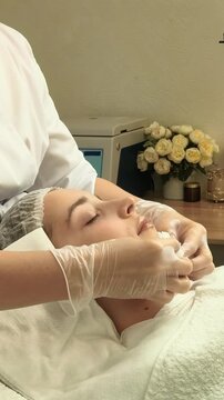 Esthetician removes cleanser from a teenage girl's face in a beauty clinic, professional skincare, gentle cleansing, healthy complexion, cosmetic care.