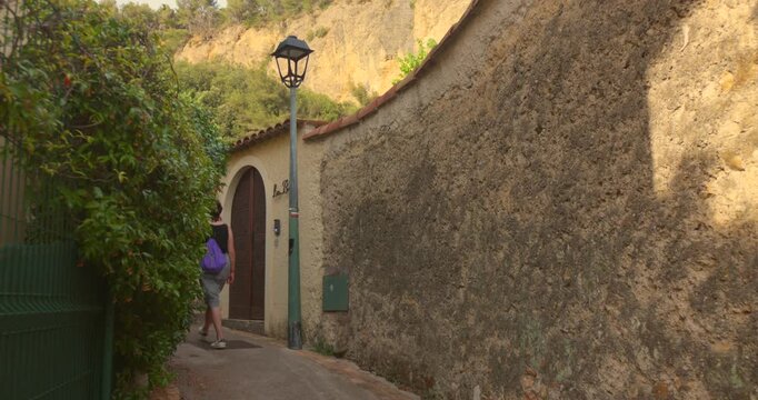 oman walking through a charming, narrow street in the historic medieval village of Roquebrune-Cap-Martin, French Riviera. Scenic stroll in a picturesque, old european village.
