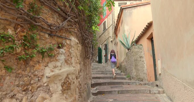 Woman walking up historic stone steps in the narrow, charming alleys of the medieval village of Roquebrune-Cap-Martin, French Riviera. Scenic stroll in a picturesque, authentic European setting, trave