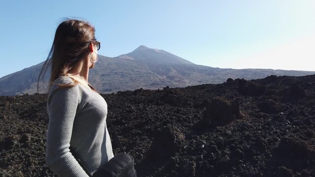 woman looking at the scenic view of Mount Teide. Her hair is blowing in the wind inside the Teide National Park in Tenerife