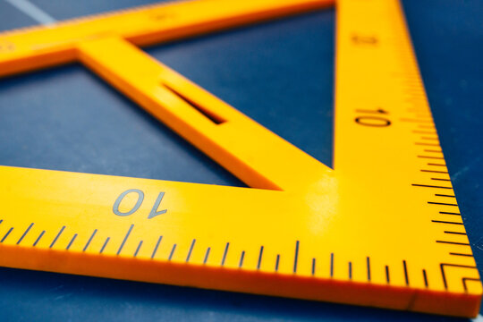Close-up photography of a yellow set square ruler on a blue surface